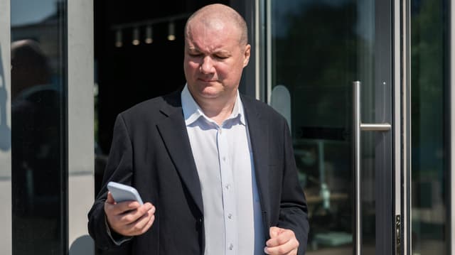 Mies avaamassa sovellusta puhelimessa