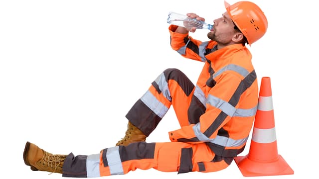 työmies nojaa huomiovaatteet päällään kartioon ja juo pullosta vettä
